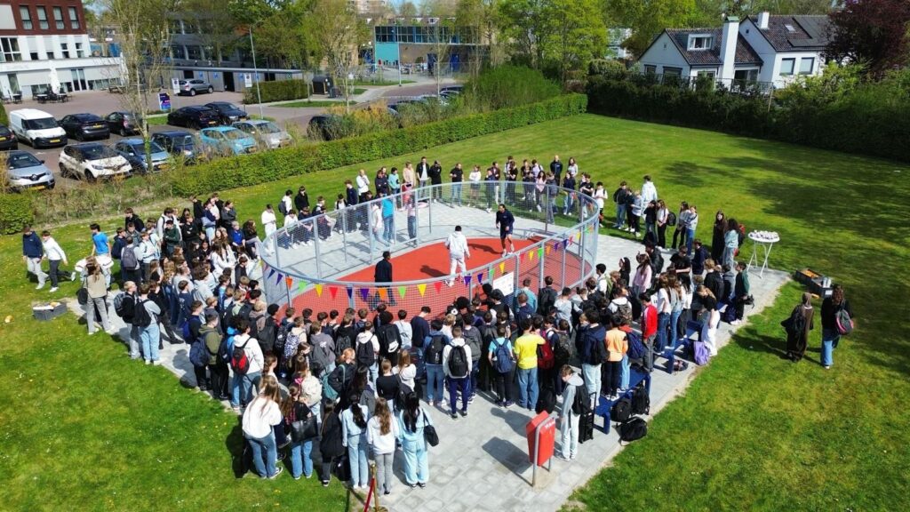 Luchtfoto van het schoolplein van CSW Walcheren met honderden leerlingen rond de pannakooi.