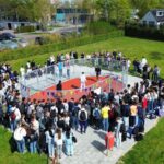 Luchtfoto van het schoolplein van CSW Walcheren met honderden leerlingen rond de pannakooi.