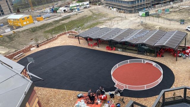 Overzicht van de rode sportvloer en basketbalpaal